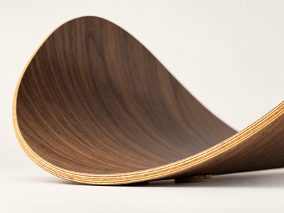 A close-up of of the Aspen's edge, showing a dark brown wood grain pattern on the inner side and lighter tan layered edges, set against a clean off-white background.