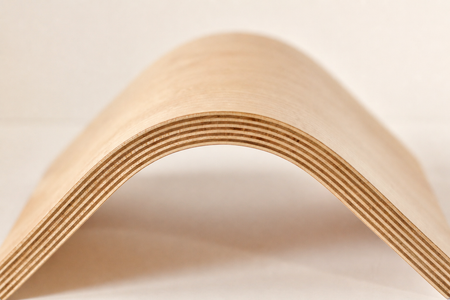 Close-up of the exposed veneer layers along a curved bent-plywood furniture edge.