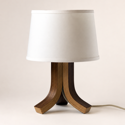 A modern table lamp with a white fabric drum shade and a sculptural three-legged base made of layered wood veneer in dark and medium brown tones, shown against a plain light beige background.